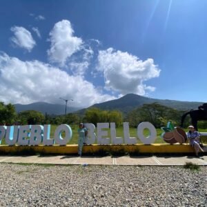 Paisaje de Pueblo Bello con su letrero y las montañas de la Sierra Nevada de Santa Marta
