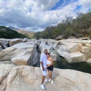 Pareja disfrutando un río entre rocas y montañas en el territorio vallenato